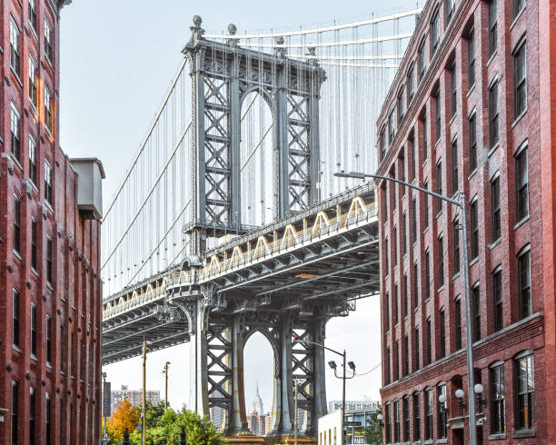 Iconic view of Manhattan Bridge from Washington Street. Red brick street buildings leading to the bridge at dusk. Brooklyn. NYC, USA Iconic view of Manhattan Bridge from Washington Street. Red brick street buildings leading to the bridge at dusk. Brooklyn. NYC, USA. brooklyn bridge stock pictures, royalty-free photos & images