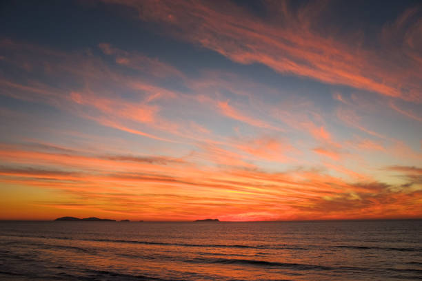 een bewolkte en kleurrijke zonsondergang op de vreedzame kust van mexico - northern light stockfoto's en -beelden