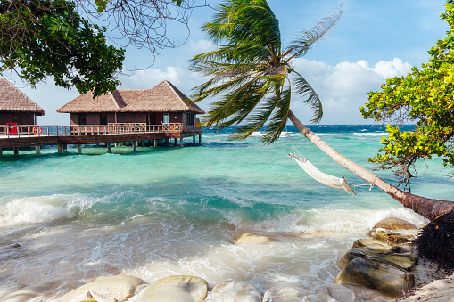 Paradise beach scene with white sand, ocean, and water bungalows, Maldives