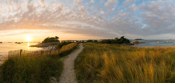 idyllic coast panorama at sunset with sandy footpath leading into the distance Panorama of idyllic coast and beach at sunset with sandy footpath leading into the distance finistere stock pictures, royalty-free photos & images