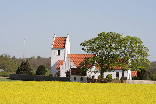 Idyllic country side parish church behind oilseed rape field stock photo