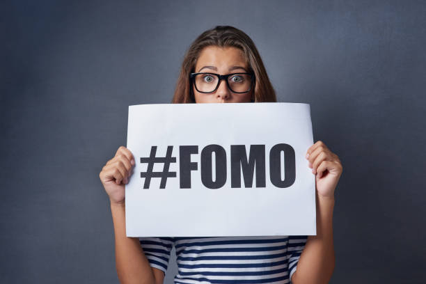 If it happened online it must be real Studio shot of an attractive young woman holding a sign with #FOMO printed on it against a gray background fomo photos stock pictures, royalty-free photos & images