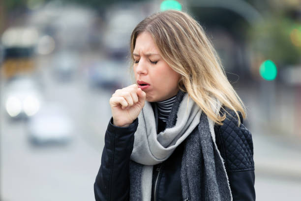 Illness young woman coughing in the street. stock photo
