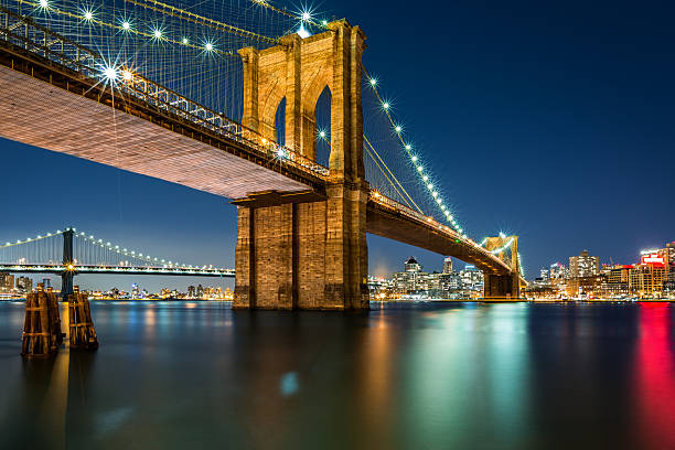 Illuminated Brooklyn Bridge by night Illuminated Brooklyn Bridge by night as viewed from the Manhattan side - very long exposure for a perfectly smooth water brooklyn bridge stock pictures, royalty-free photos & images