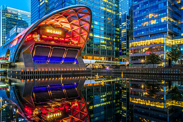 Illuminated Crossrail Place in Canary Wharf London, UK - August 29, 2016 - View of Canary Wharf office buildings at dusk from across the North Dock, with illuminated Crossrail station in the foreground. canary wharf stock pictures, royalty-free photos & images