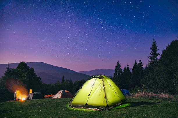 illuminated  green  tent under stars at night  forest - tent imagens e fotografias de stock