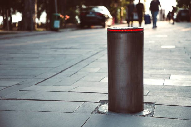Illuminated retractable automatic traffic bollard protects pedestrian zone. Safety concept. Blurred people on background. stock photo