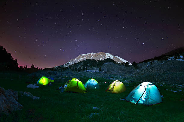 Illuminated yellow camping tent under stars at night stock photo