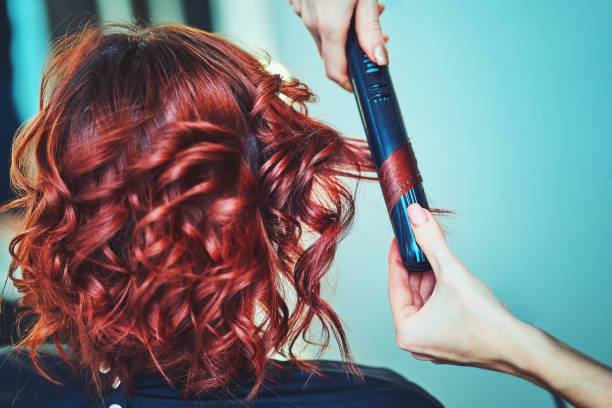 Image of a hairdresser applying extensions to a client's hair stock photo