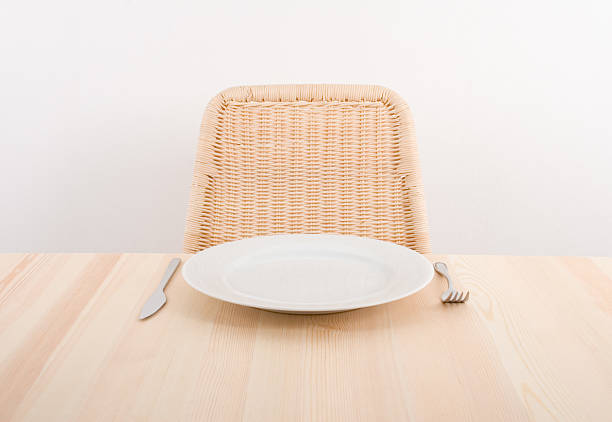 Image of a single plate with an empty seat at a table stock photo