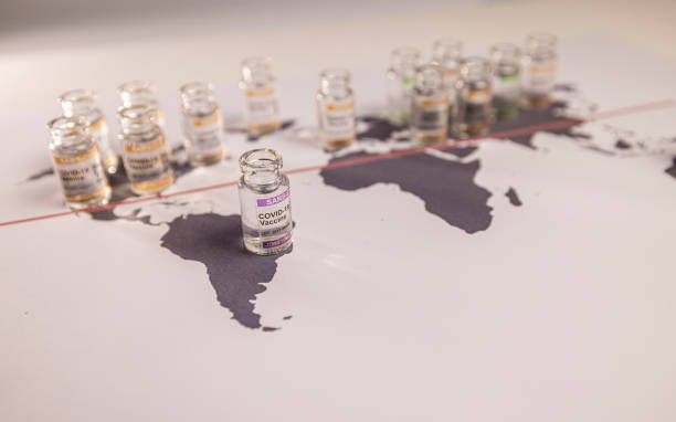 Image of a world globe map with vials for the global SARS/COVID pandemic vaccine war, with vaccine hoarding, restricting equal access to vaccines across the world, counteracted by the Covax programme and global vaccine alliance stock photo