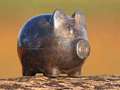 istock Image of tarnished metal piggy bank pig on stone-wall, blurred-background 469732960