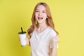 黄色の背景にミルクティーを飲むアジアの少女の画像