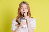 黄色の背景にミルクティーを飲むアジアの少女の画像