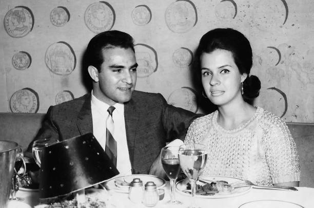 Image taken in the 60s - hispanic young man posing with his caucasian young girlfriend Black and white Image taken in the 60s - hispanic young man posing with his caucasian young girlfriend having dinner sitting in a restaurant table restaurant photos stock pictures, royalty-free photos & images