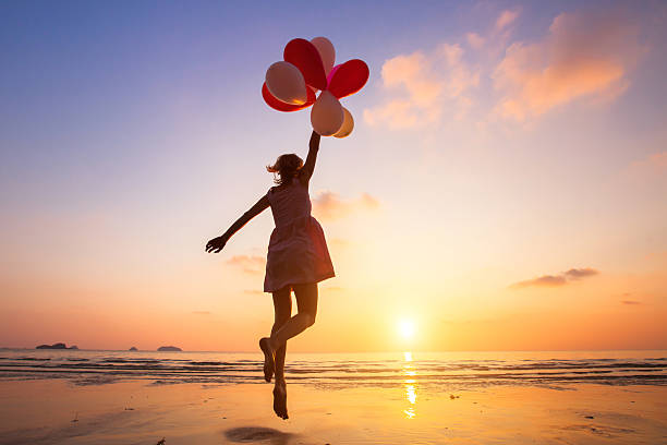 imagination, happy girl flying on multicolored balloons, dreamer imagination, happy girl jumping with multicolored balloons at sunset on the beach, fly, follow your dream day dreaming stock pictures, royalty-free photos & images