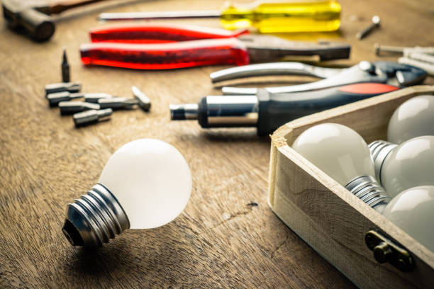 Light bulbs and wood box with hardware tools on the desk, implement...