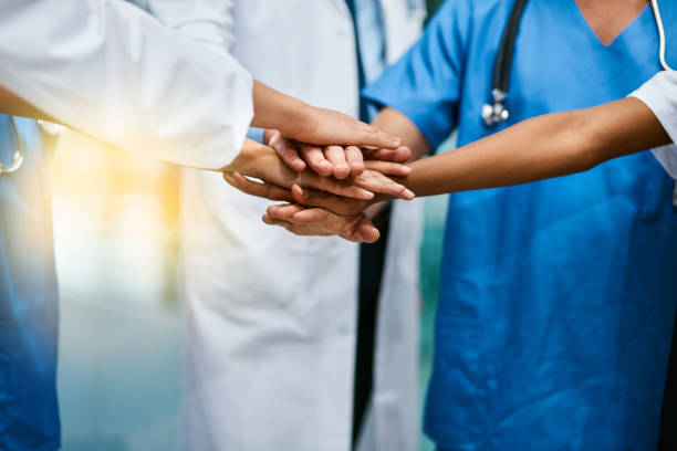 In it to saves lives together Shot of a group of unrecognisable medical practitioners joining their hands together in unity dedication stock pictures, royalty-free photos & images