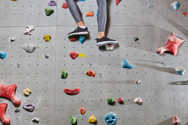 In process of climbing Lower part of climber legs in leggins and sports-shoes standing on grips of wall bouldering stock pictures, royalty-free photos & images