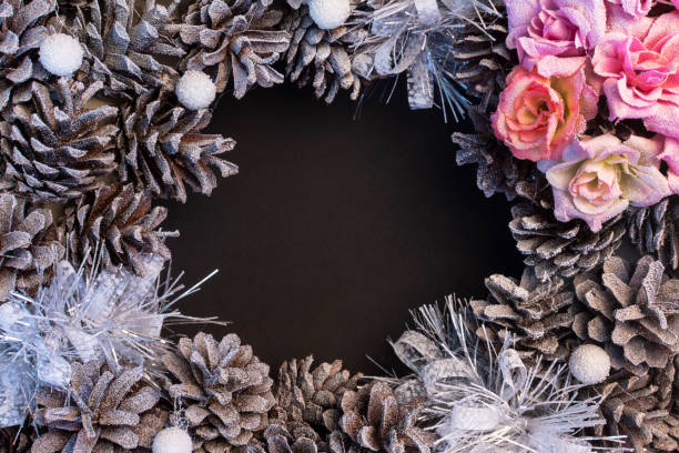 In the center of the black background is a place for an inscription, copy space. Around the frame of cones and flowers. Beautiful Christmas mockup. stock photo