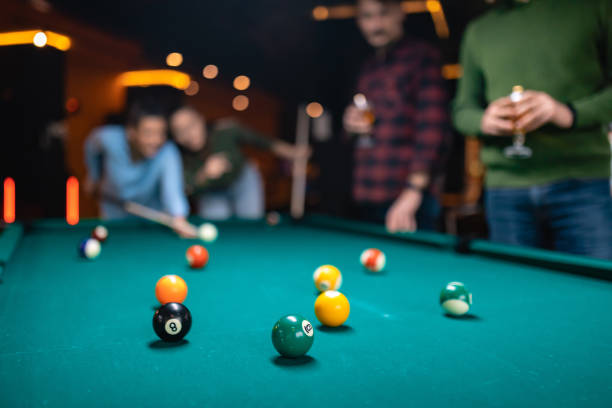 In the close-up are billiard balls, while in the background is a group of people playing billiards. Blurred background stock photo