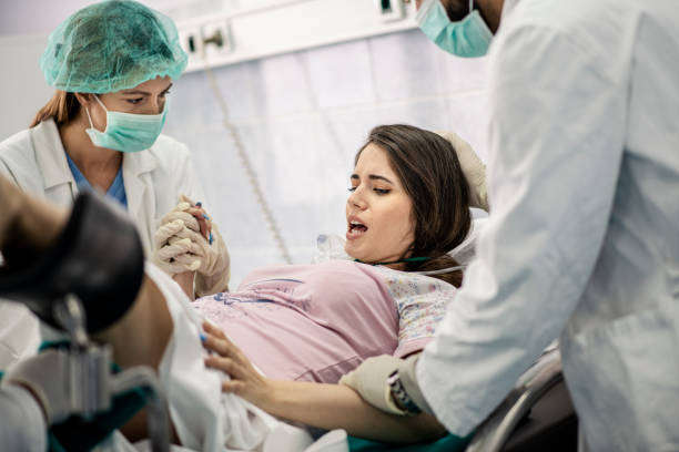 In the Hospital Woman Giving Birth Support, Obstetricians Assisting. Modern Delivery Ward with Professional Midwives In the Hospital Woman Giving Birth Support, Obstetricians Assisting. Modern Delivery Ward with Professional Midwives childbirth stock pictures, royalty-free photos & images