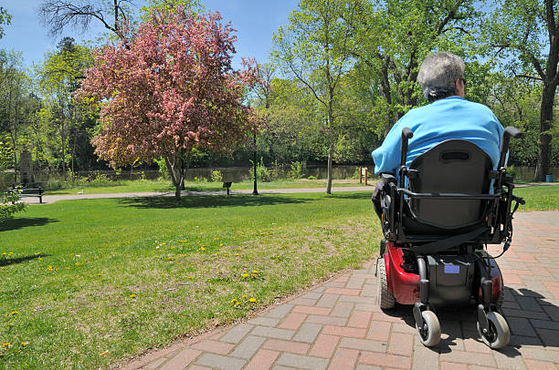 In the Park Middle aged woman in her power wheel chair enjoying a city park on a nice spring day. multiple sclerosis stock pictures, royalty-free photos & images
