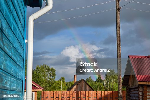 istock In the rain the sky visible rainbow over village. 1140132105