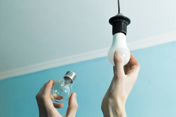 Incandescent lamp is changed to LED light by the hands of a man. Energy saving. stock photo