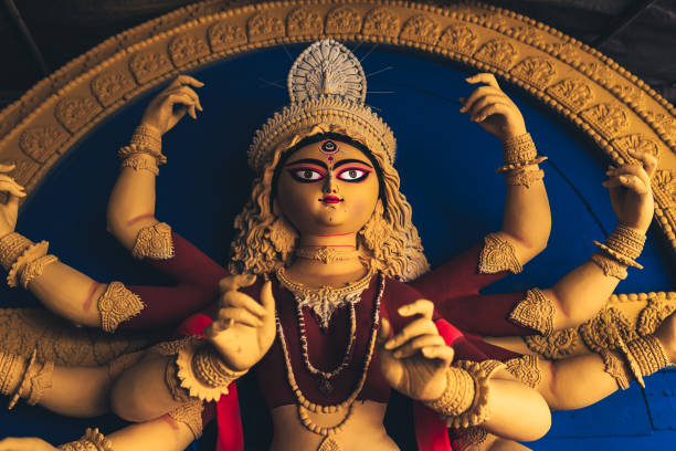 Indian Durga Goddess idol being made with clay for Hindu festival of Navratri. Close up of yellow colour Durga goddess idol with red clothing newly made at a workshop for the religious hindu festival. Indian goddess with multiple arms. hindu god stock pictures, royalty-free photos & images