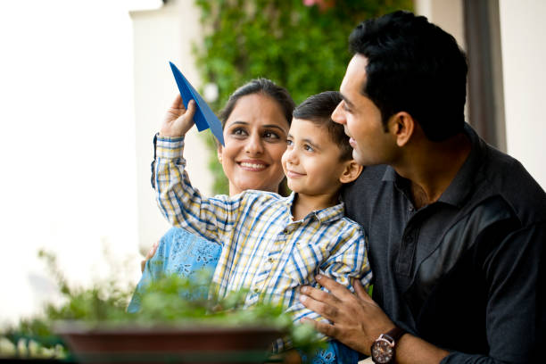 Indian family playing with paper airplane Happy parents with son throwing paper airplane in air indian ethnicity stock pictures, royalty-free photos & images
