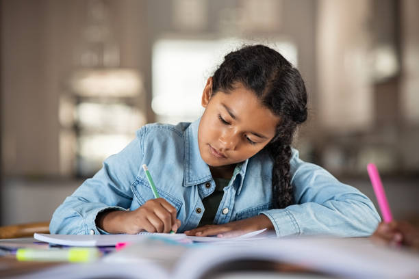 Indian little girl studying at home Middle eastern girl doing homework writing and reading at home. Concentrated beautiful indian female child writing in her notebook. Focused latin schoolgirl studying and preparing for exams. 8 9 years stock pictures, royalty-free photos & images