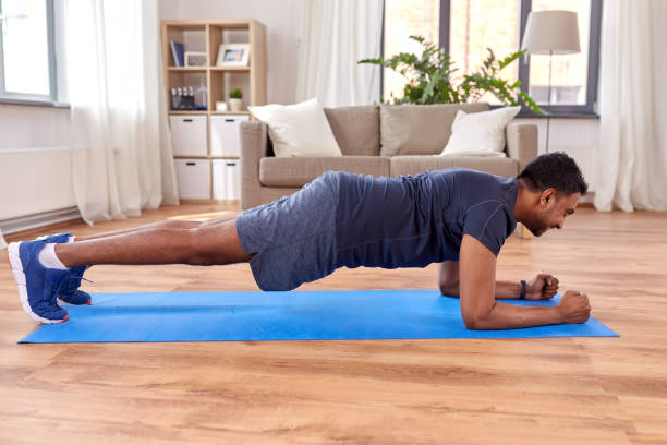 indian man doing plank exercise at home stock photo