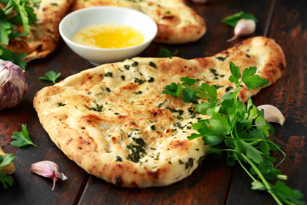 Indian naan bread with garlic butter on wooden table Indian naan bread with garlic butter on wooden table. naan bread stock pictures, royalty-free photos & images
