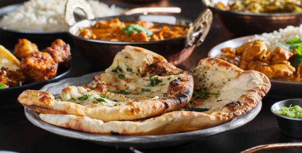 indian naan bread with herbs and garlic seasoning on plate indian naan bread with herbs and garlic seasoning on plate close up naan bread stock pictures, royalty-free photos & images