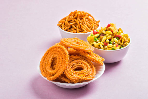Indian Snack : Chakli, chakali or Murukku and Besan (Gram flour) Sev and chivada or chiwada on pink background. Diwali Food stock photo