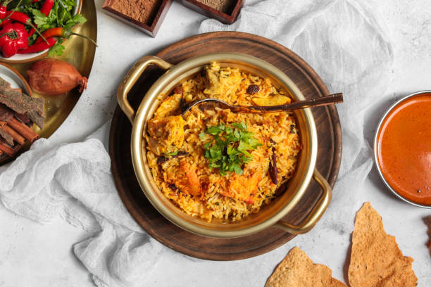 Indian tandoori chicken biriyani dish with yellow saffron rice, cashew nuts and pappadum bread stock photo