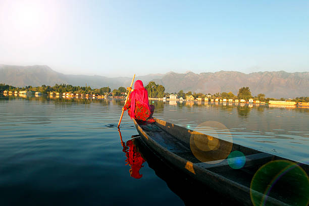 Indian Woman boating in Dal Lake, Srinagar, India. Indian women returning home in evening after collecting lotus leafs, which they use to feed cattle and sometime they use to sell it cattle's owner. This is part of daily life of majority of women in Srinagar, Jammu and Kashmir, India. jammu and kashmir stock pictures, royalty-free photos & images