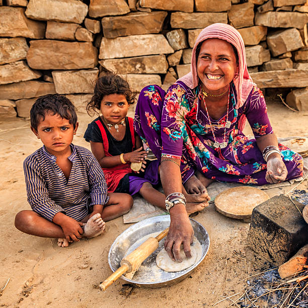 Indian woman preparing food - chapatti, flat bread, desert village Indian woman preparing food - chapati, flatbread, desert village, India. Her children are waiting for breakfast just next to her chapatti stock pictures, royalty-free photos & images