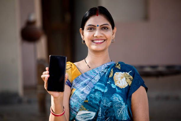 Indian woman showing mobile phone Rural Indian woman in sari showing mobile phone village photos stock pictures, royalty-free photos & images