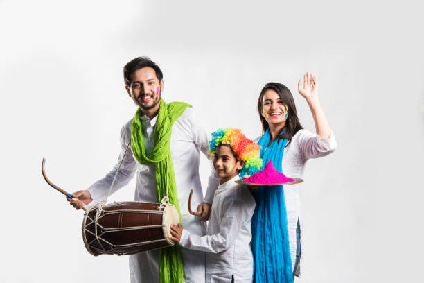 Indian young couple with kid celebrating holi festival. Dancing and playing drums and holding plate full of colours Indian young couple with kid celebrating holi festival. Dancing and playing drums and holding plate full of colours holi photos stock pictures, royalty-free photos & images