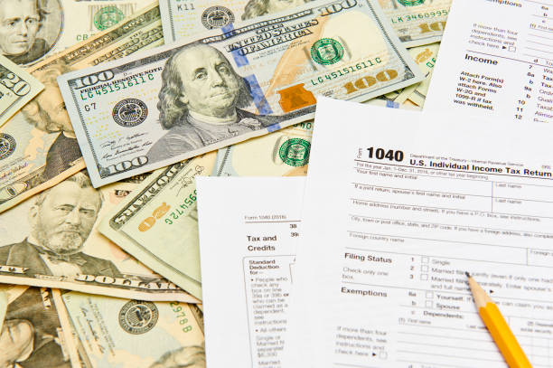 1040 Individual Tax Return form on top of a table full of paper money. stock photo