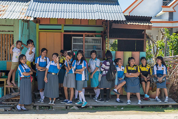 Indonesian school girls waiting outdoors Tentena, Sulawesi, Indonesia - August 21, 2014: Group of school girls of indonesian ethnicity in blue and white uniform smiling while looking at the camera in Tentena, Sulawesi, Indonesia. indonesian girl stock pictures, royalty-free photos & images