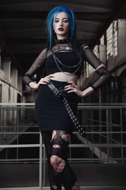 Indoor portrait of seductive goth (deathrock) girl dressed in black skirt, leaky blouse and pantyhose. Dark beauty stock photo