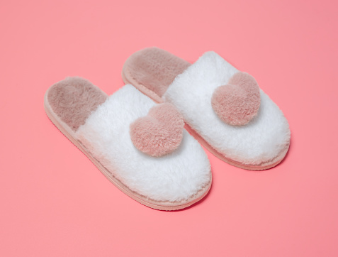 Indoor women's slippers pink with white on a pink background.