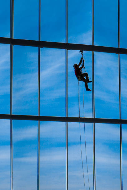 Industrial climber hangs from ropes inside building stock photo