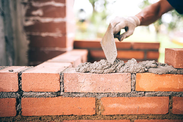 industrial Construction bricklayer worker building walls with bricks, mortar stock photo
