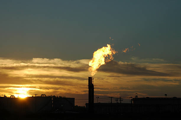 Industrial plant with fuel bowsers and gas flare into sky stock photo
