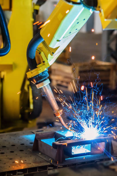 Industrial robot welds a part. Sparks and smoke stock photo