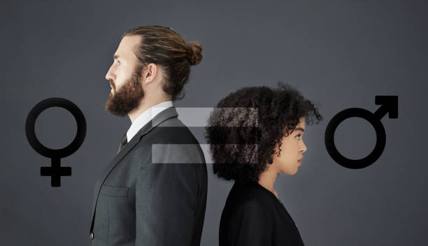 Inequality will never be a side issue Shot of two corporate businesspeople posing together in studio with gender symbols inserted in the background gender stereotypes stock pictures, royalty-free photos & images